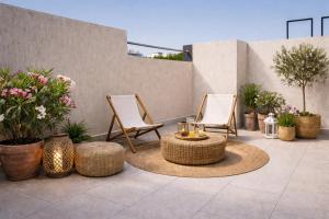 two chairs and a table on a patio with plants at Appartement moderne à 5 min de la plage de Mehdia Vacances idéales 2026 in Mehdiya-Plage