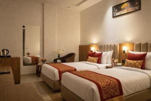 a hotel room with two beds and a mirror at Hotel Rs Vista - Agra in Agra