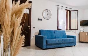 a blue couch in a living room with a clock on the wall at ALMA'RE Le Trame di KaSa Experience in Porto Ottiolu