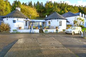 an old car parked in front of a white house at Appin's Coorie Nook in Appin
