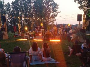 a group of people sitting on the grass watching a concert at Stodoła Pod Gwiazdami - Jezioro Głuszyńskie in Orle