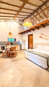 a bedroom with a bed and a table and a kitchen at Vila Alta Caraíva in Caraíva