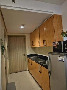 a kitchen with wooden cabinets and a refrigerator at MOA staycation Shore 1 tower D in Manila