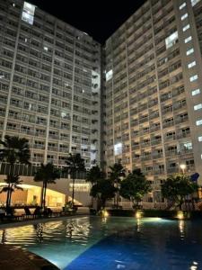 a large building with a large swimming pool at night at MOA staycation Shore 1 tower D in Manila