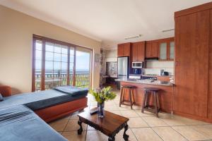 a bedroom with a bed and a kitchen with a balcony at Coastline Serenity in Kleinmond