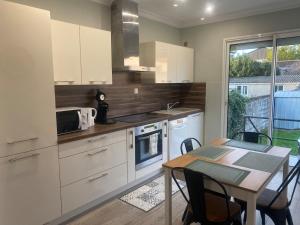 a kitchen with white cabinets and a table and a dining room at Maison Mylan, simple and practical! in Cholet