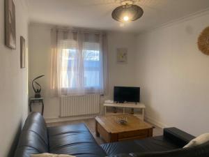 a living room with a leather couch and a table at Maison Mylan, simple and practical! in Cholet