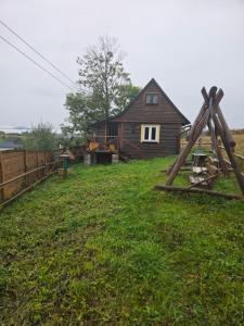 a house in a field with a yard with a fence at Chata Między Górami in Zalesie