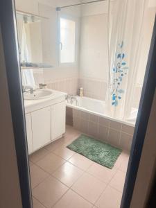 a bathroom with a tub and a sink and a mirror at Maison à louer in Valence