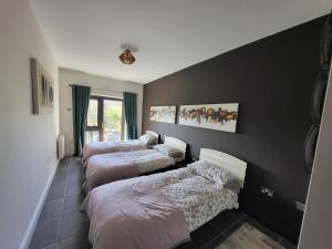 a bedroom with three beds and a black wall at the ring of kerry riverside apartment in Killorglin