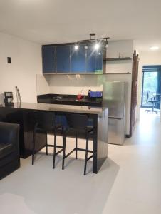 a kitchen with a counter with chairs and a refrigerator at Eco Paradise 228 in Cumbuco