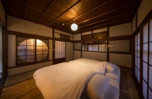 a bedroom with a white bed and two windows at 3000平米の元醤油名家邸宅, 日本庭園, 蔵Bar, サウナ, 出張料理, フルサービスの宿 in Shodoshima