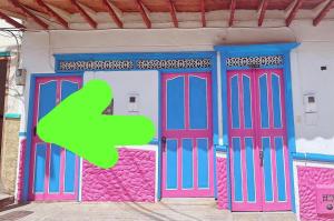 a building with purple doors with a green arrow at Aloja-T Hostal Jericó in Jericó