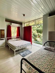 two beds in a room with red curtains at The Grey House in Bacong +24 photos