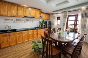 a kitchen with wooden cabinets and a table and chairs at Villa Thung Lũng Hồng 2 in Ấp Kim Thạch