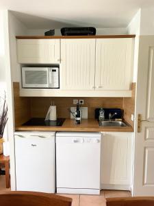 a kitchen with white cabinets and a microwave and a sink at Séjour 4 personnes - Pays Basque in Uhart-Cize +2 photos