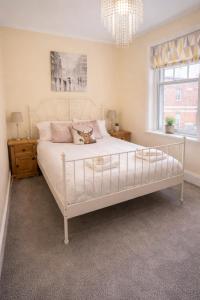 a bedroom with a large white bed with a chandelier at Clock Tower Flats Morpeth in Morpeth