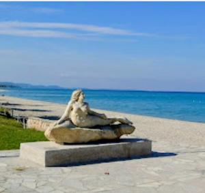 a statue of a woman sitting on a rock on the beach at NiRa house in Pefkochori
