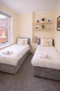 two beds in a room with a window at Clock Tower Flats Morpeth in Morpeth