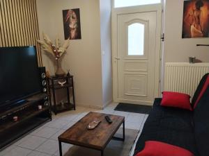 a living room with a couch and a table and a tv at Yapas in Beaumont-sur-Sarthe