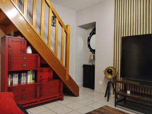 a living room with a staircase and a tv at Yapas in Beaumont-sur-Sarthe