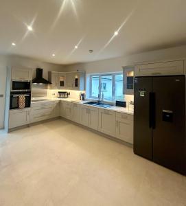 a large kitchen with white cabinets and a black refrigerator at Modern house Boyle in Boyle