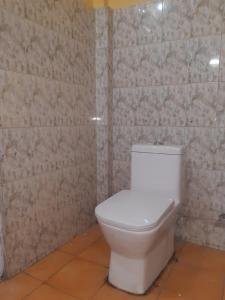 a white toilet in a bathroom with a tiled wall at Himalayan Heritage Stay in Darjeeling