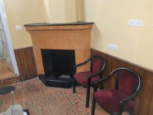 a living room with two chairs and a fireplace at Himalayan Heritage Stay in Darjeeling