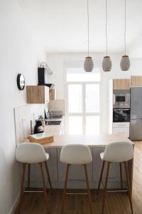 a kitchen with a wooden counter and two white stools at Apartamento Aljibe in Arcos de la Frontera