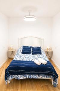 a bedroom with a bed with blue pillows and two tables at Apartamento Aljibe in Arcos de la Frontera