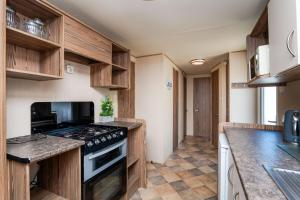 a kitchen with wooden cabinets and a stove top oven at Coastal Caravan at Seton Sands -Near Edinburgh in Port Seton +28 photos