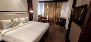 a hotel room with a large white bed and a chair at Hotel Regalia in Bathinda