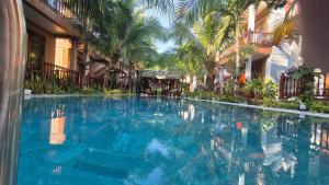 a large blue swimming pool in a building with palm trees at Valentina Resort & Spa Phu Quoc in Phú Quốc