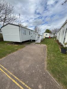 a white mobile home parked next to a building at Seaside Lodge Haven in St Osyth in Jaywick Sands