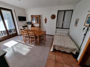 a living room with a table and chairs and a room with a bed at Casa Enrico in Pieve Di Ledro