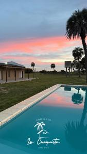 a swimming pool in front of a house with a palm tree at Complejo La Conquista in Goya