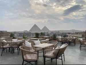 a patio with tables and chairs with pyramids in the background at The Grand Delta Hotel in Cairo
