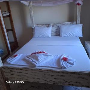 a bed with white sheets and red flowers on it at Orange apartments 3 in Watamu