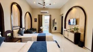 two beds in a hotel room with arched windows at Hotel Omkareshwar Jyotirling Inn in Godarpura