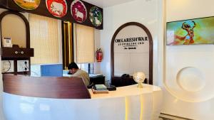 a man sitting at a desk in an office at Hotel Omkareshwar Jyotirling Inn in Godarpura
