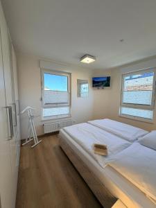 a bedroom with a large bed and two windows at Duhner Leuchturm, Ferienwohnung DL02 in Cuxhaven