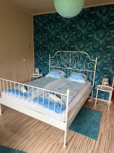 a bedroom with a bed with a green wall at Zso-Zé Apartman in Tiszafüred