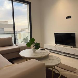 a living room with a couch and a tv and a table at Résidence Jasmin in Harqalah
