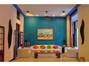 a living room with white couches and a blue wall at Villa Capers in Colombo