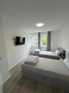a bedroom with two beds and a flat screen tv at Ruheblick Apartment Essen in Essen +3 photos