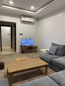 a living room with a couch and a flat screen tv at Talya Apartment in Mecca