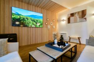 a living room with a table and a tv on the wall at Les cottages du parc in Roubaix