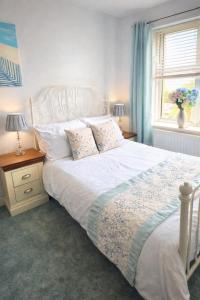 a bedroom with a white bed and a window at Sea Thrift Nook Amble in Amble