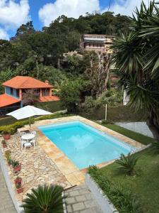 a swimming pool with a table and an umbrella at Casa Au Clair de Lune Terê in Teresópolis