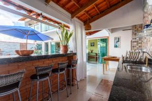 a kitchen with a bar with chairs and a sink at Casa de temporada Âncora dos Sonhos Pirenópolis Goiás in Pirenópolis